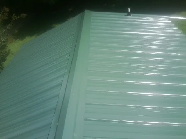 New green metal panels meeting at the ridge of a roof — Flat Roof Repair work by our crew in Scurry