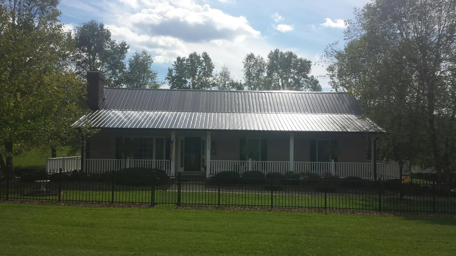 Gray metal roof on a brick ranch with a full width front porch — Gutter Guard Installation work by our crew in Scurry