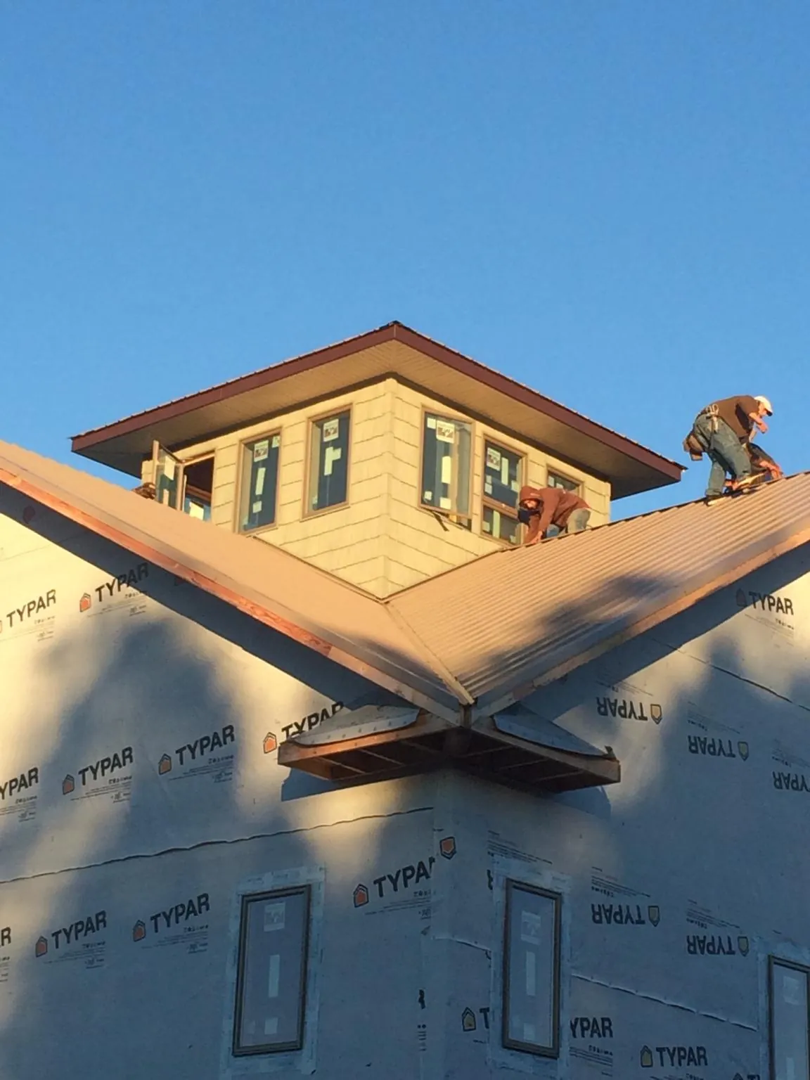 Roofers working around a rooftop cupola on a new metal roof at sunset — Roof Waterproofing in Scurry by Roofing Brothers